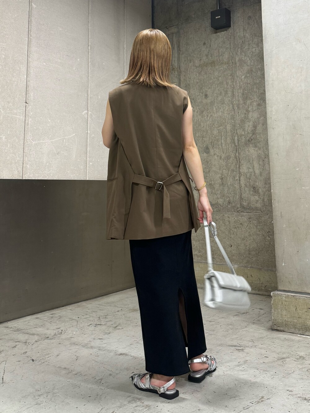 ブラウン系のベスト、ブラック系のワンピース、シルバー系のハンドバッグを着用したレディースの夏コーディネートの4枚目の写真