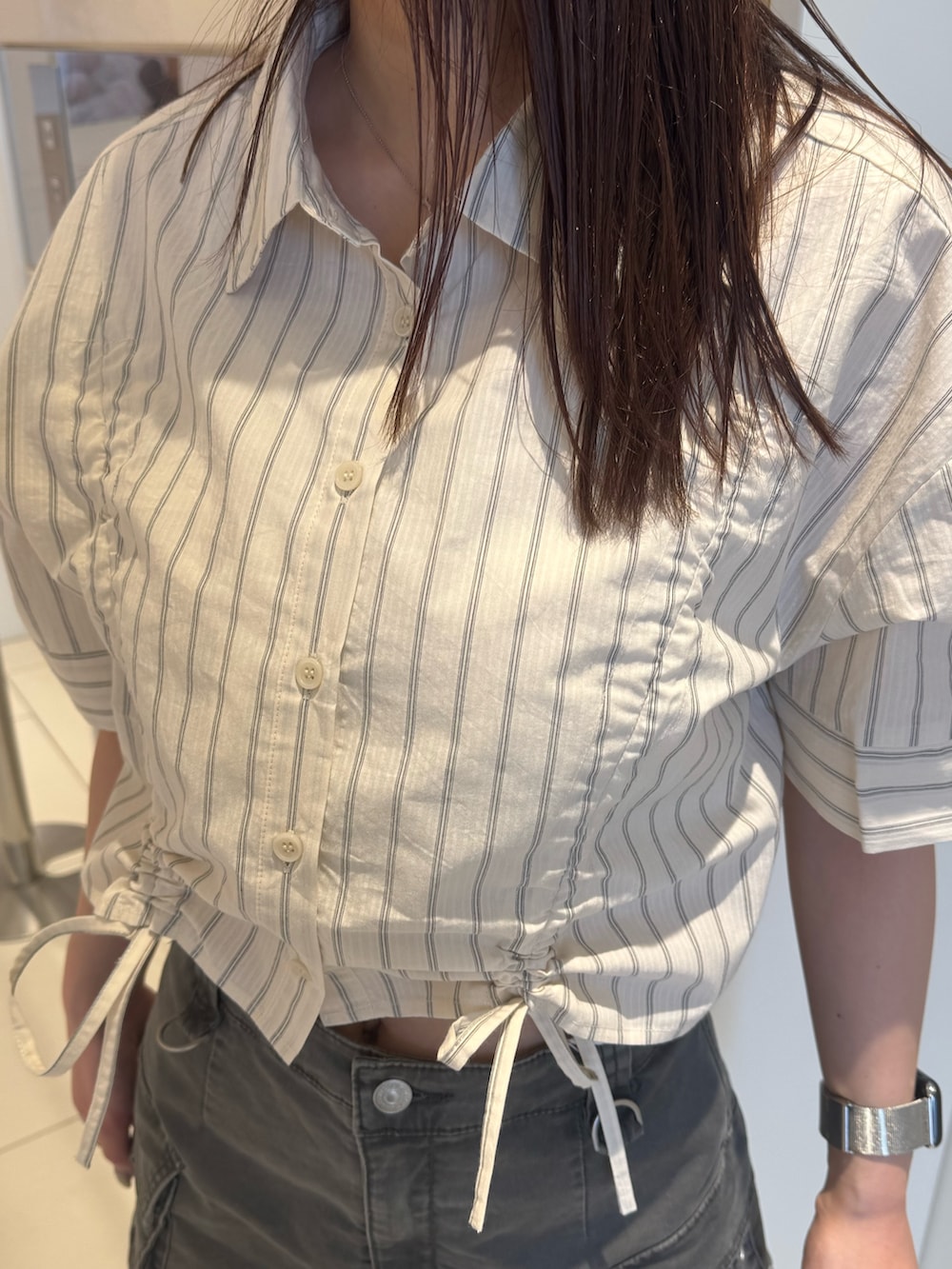 ホワイト系のシャツ/ブラウス、グレー系のスカート、ブラック系のブーツを着用したレディースの春コーディネートの6枚目の写真