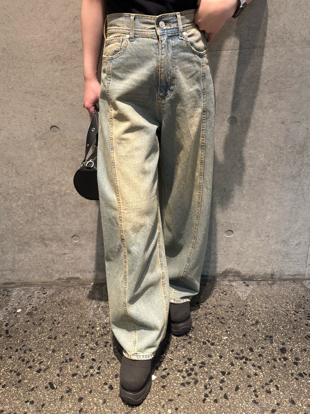 ブラック系のTシャツ/カットソー、ブルー系のデニムパンツ、ブラック系のブーツを着用したレディースの春コーディネートの6枚目の写真