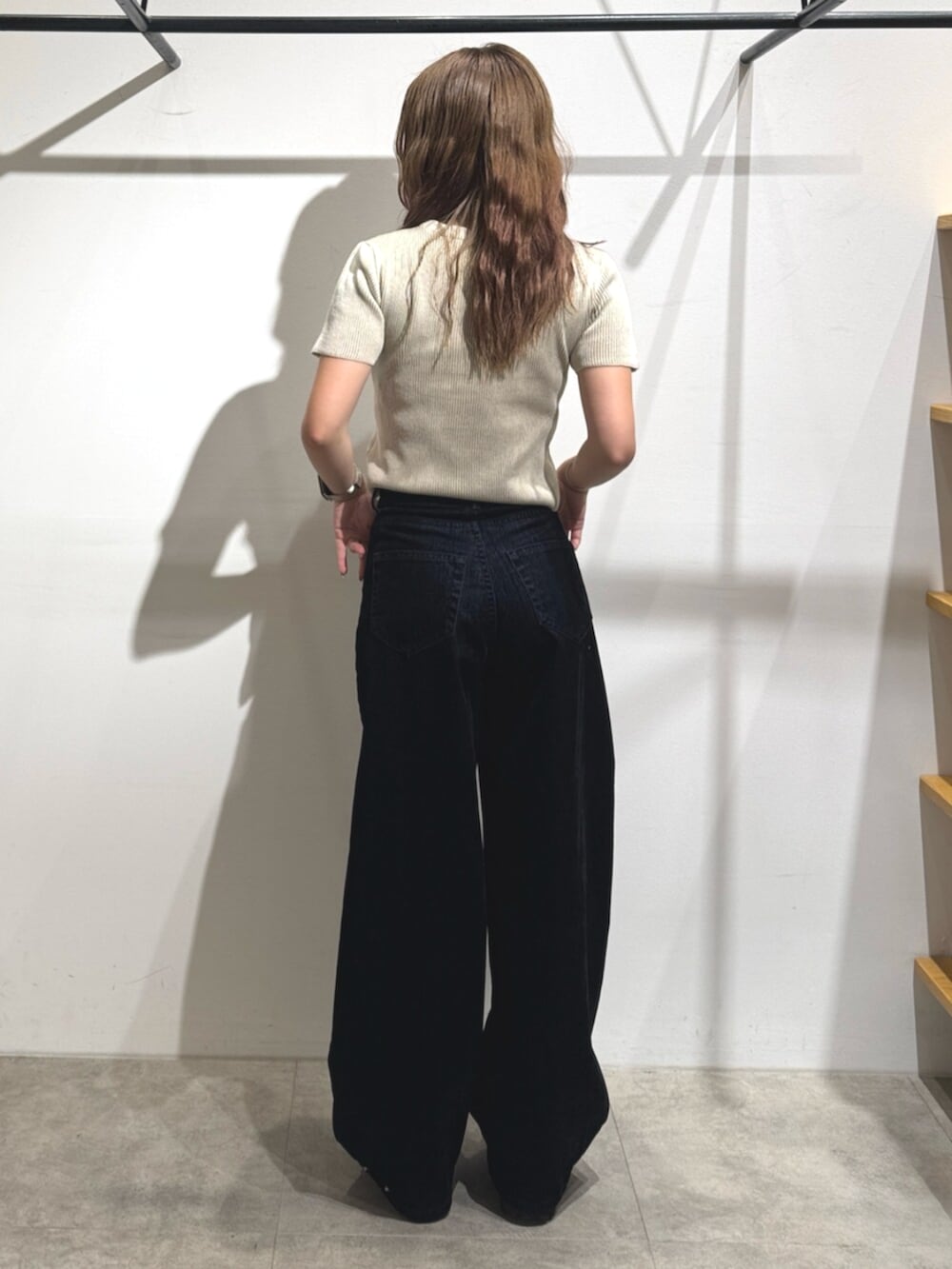 ブラック系のブーツ、ブラック系のデニムパンツ、ホワイト系のニット/セーターを着用したレディースの夏コーディネートの3枚目の写真