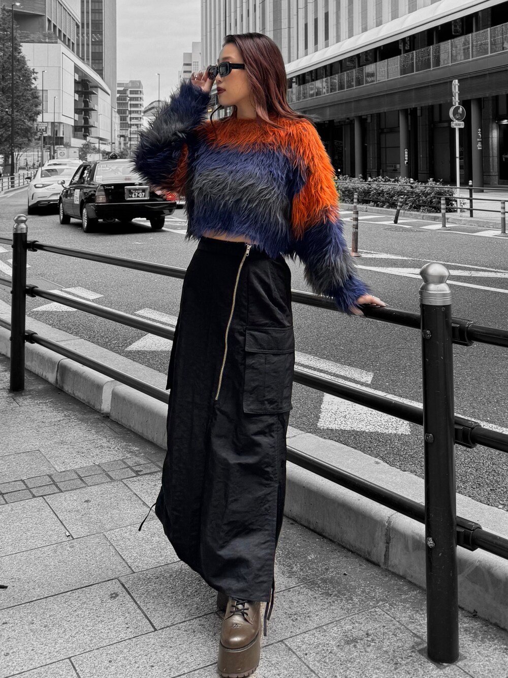 オレンジ系のニット/セーター、ブラック系のスカート、ブラウン系のブーツを着用したレディースの秋コーディネートの2枚目の写真