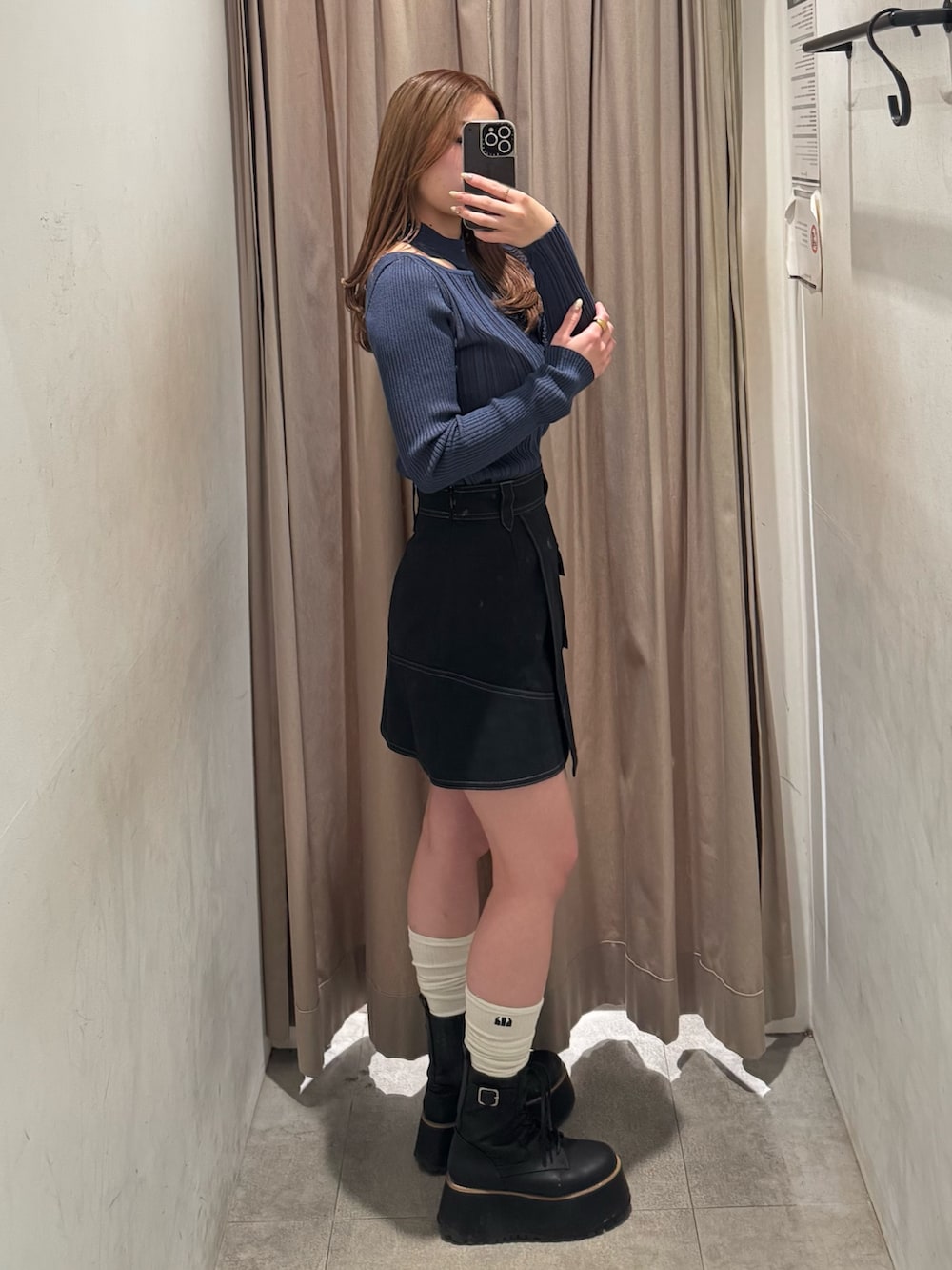 ブラック系のスカート、ブルー系のニット/セーター、ブラック系のブーツを着用したレディースの冬コーディネートの2枚目の写真