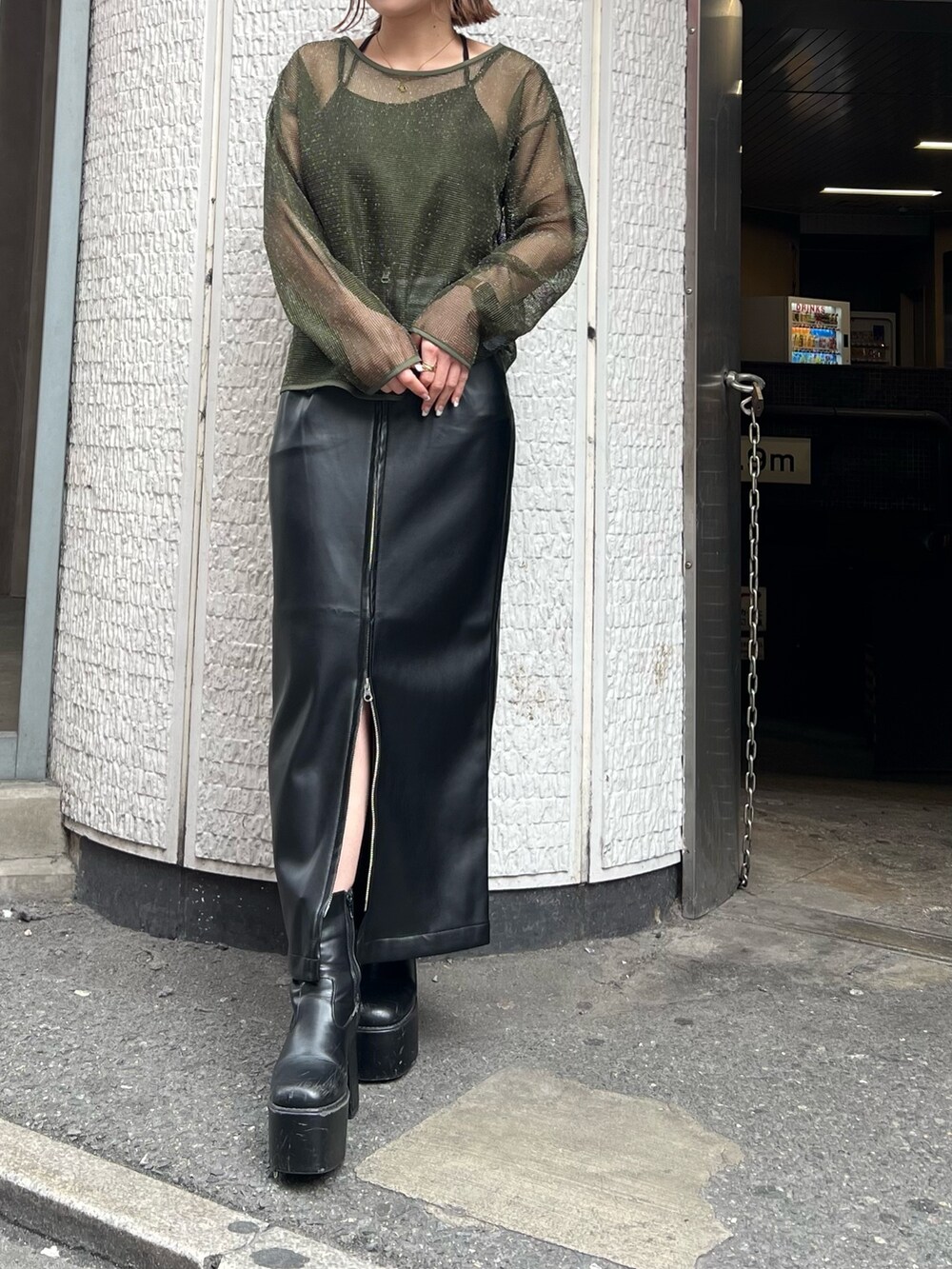 グリーン系のTシャツ/カットソー、ブラック系のスカートを着用したレディースの冬コーディネートの6枚目の写真