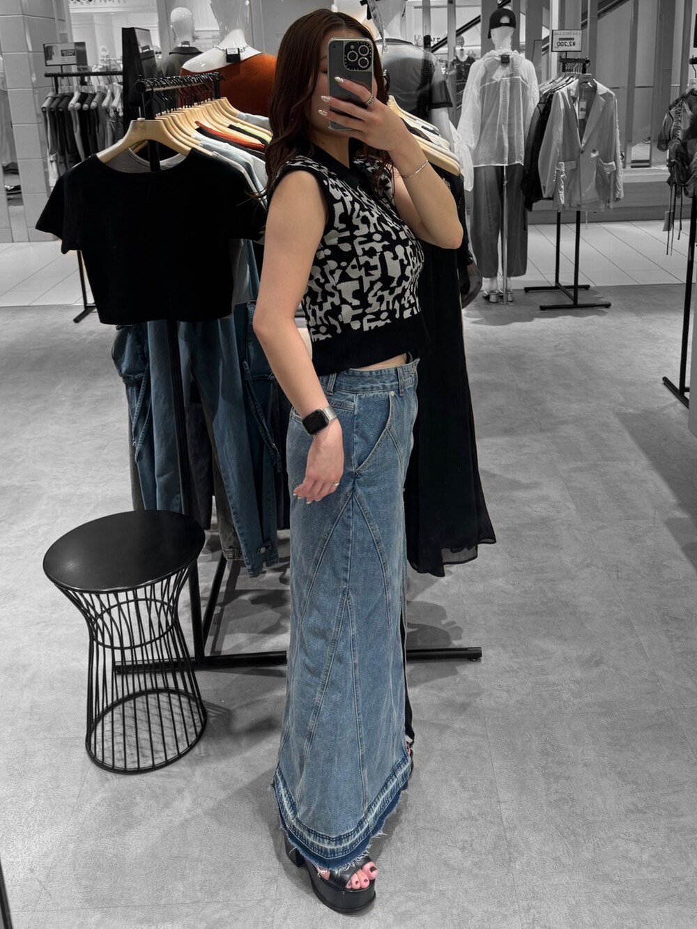 ブラック系のニット/セーター、ブルー系のデニムスカート、ブラック系のサンダルを着用したレディースの夏コーディネートの2枚目の写真