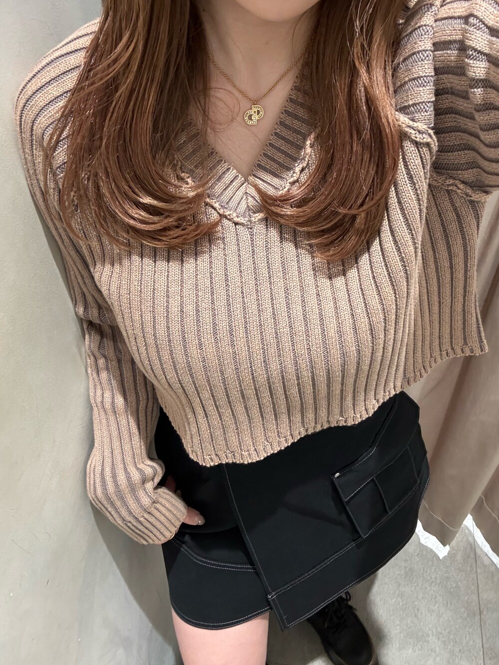 ブラック系のスカート、ベージュ系のニット/セーター、ブラック系のブーツを着用したレディースの冬コーディネートの5枚目の写真