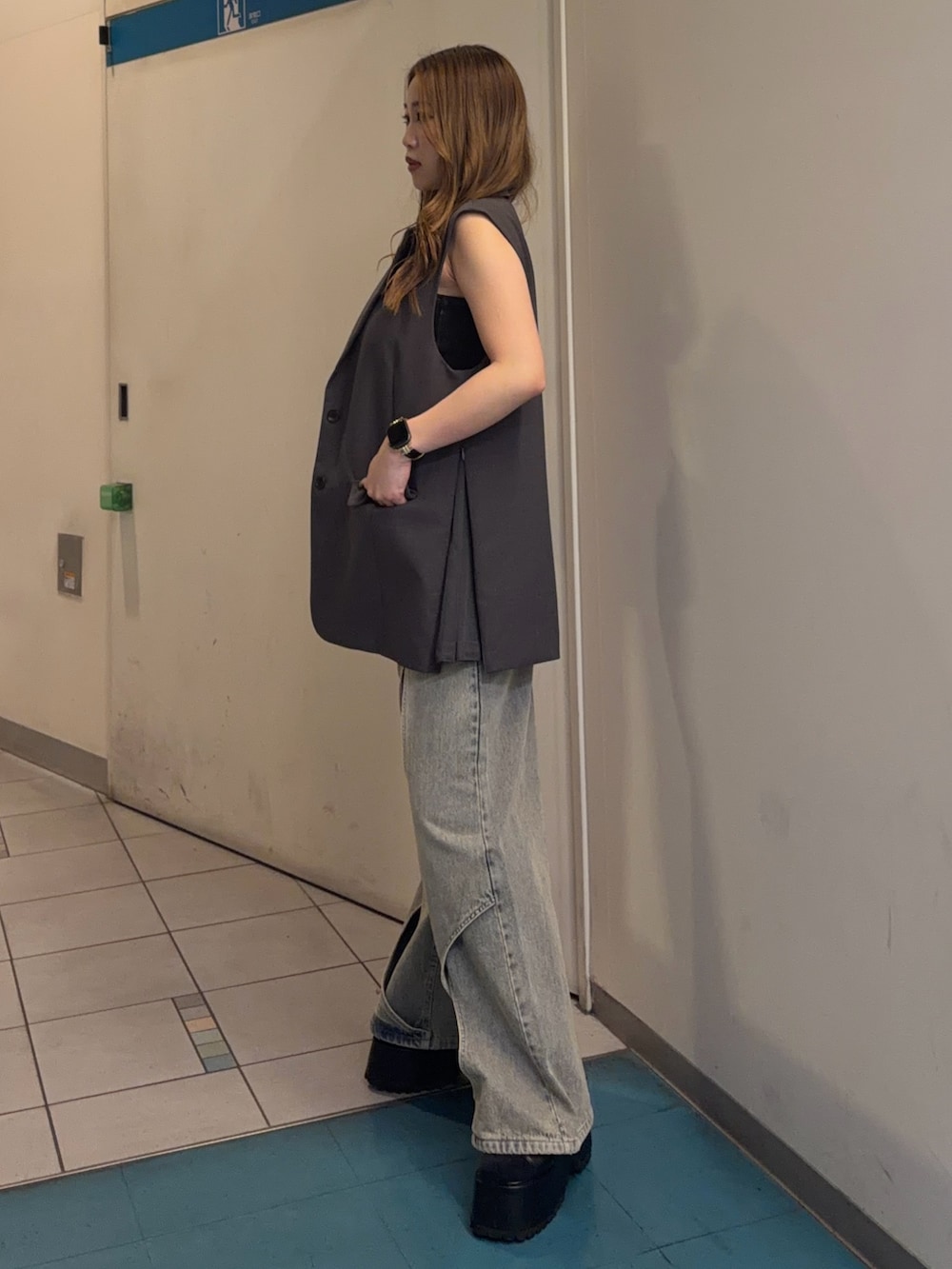 ブルー系のデニムパンツ、グレー系のベスト、ブラック系のキャミソールを着用したレディースの春コーディネートの2枚目の写真