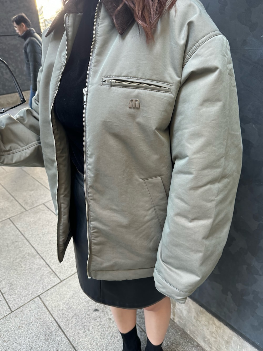 グリーン系のブルゾン、ブラック系のTシャツ/カットソー、ブラック系のスカートを着用したレディースの秋コーディネートの5枚目の写真