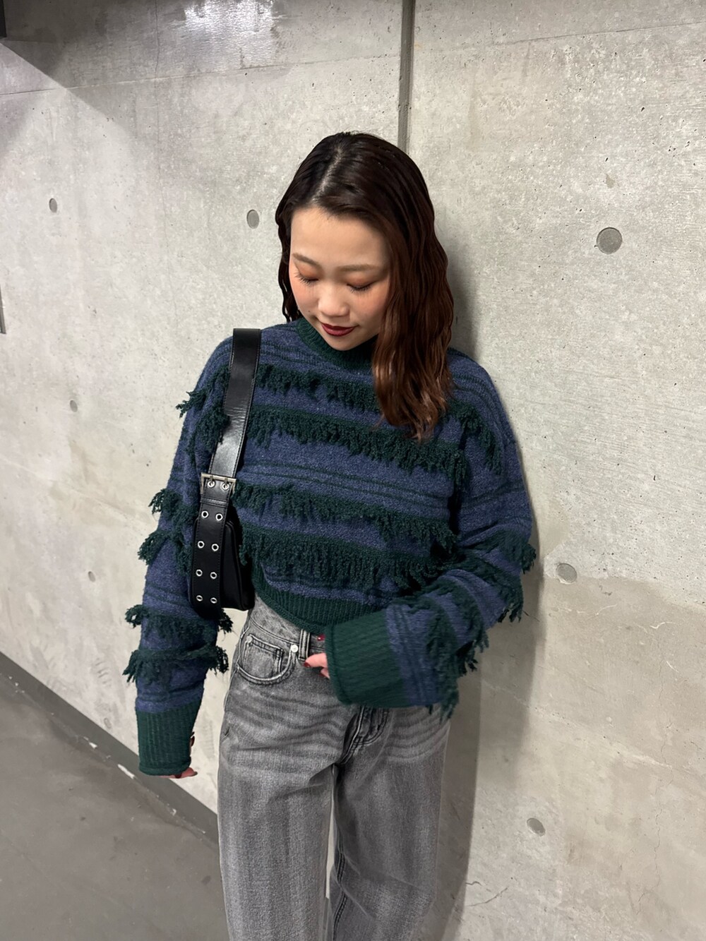 グリーン系のニット/セーター、ブラック系のデニムパンツ、ブラック系のブーツを着用したレディースの冬コーディネートの4枚目の写真