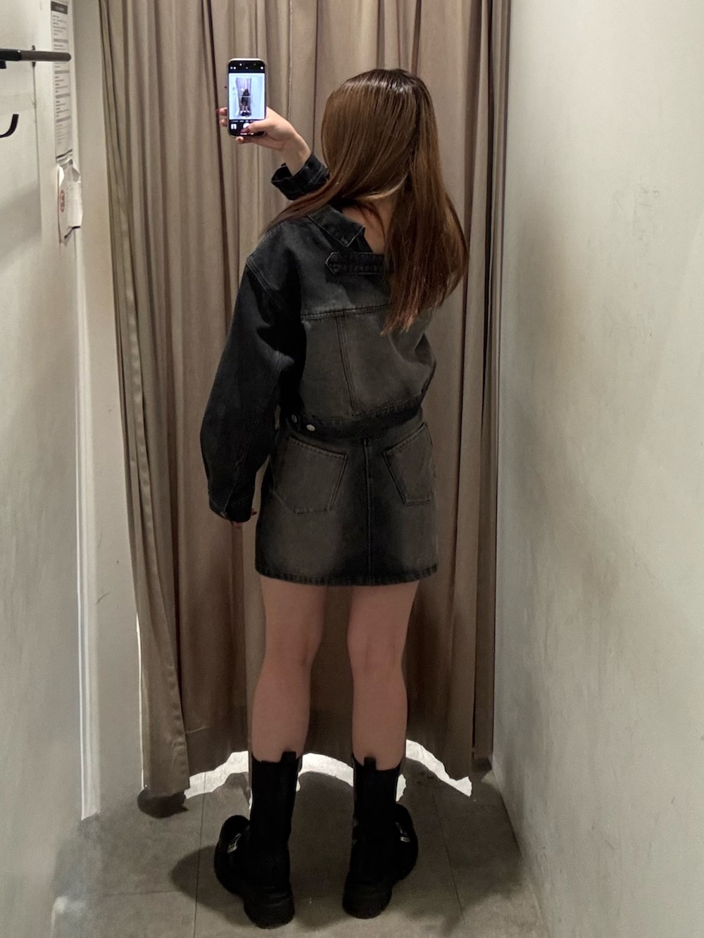 ブラック系のデニムジャケット、ブラック系のデニムスカート、ブラック系のブーツを着用したレディースの冬コーディネートの3枚目の写真