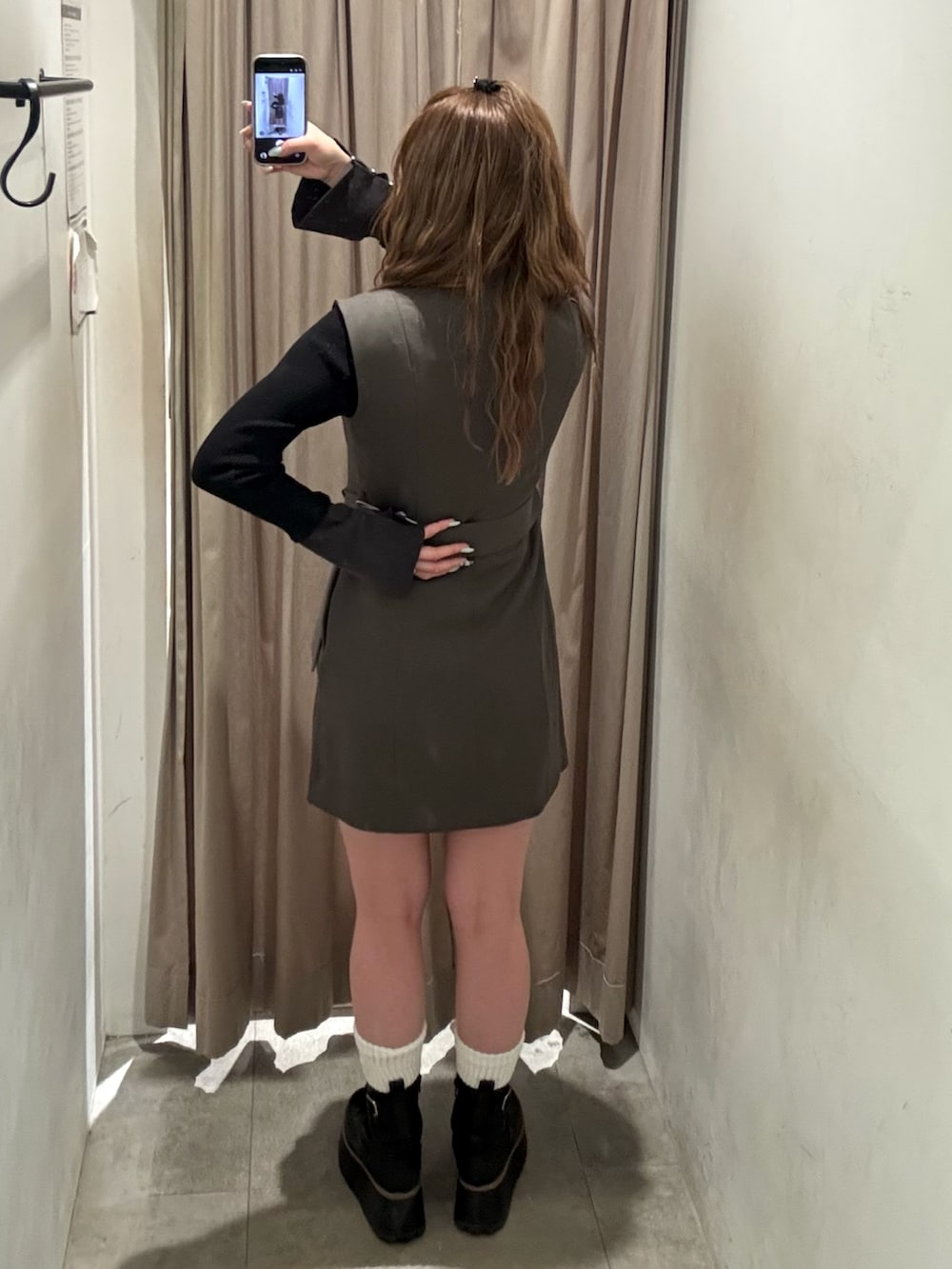 グレー系のワンピース、ブラック系のニット/セーター、ブラック系のブーツを着用したレディースの冬コーディネートの3枚目の写真