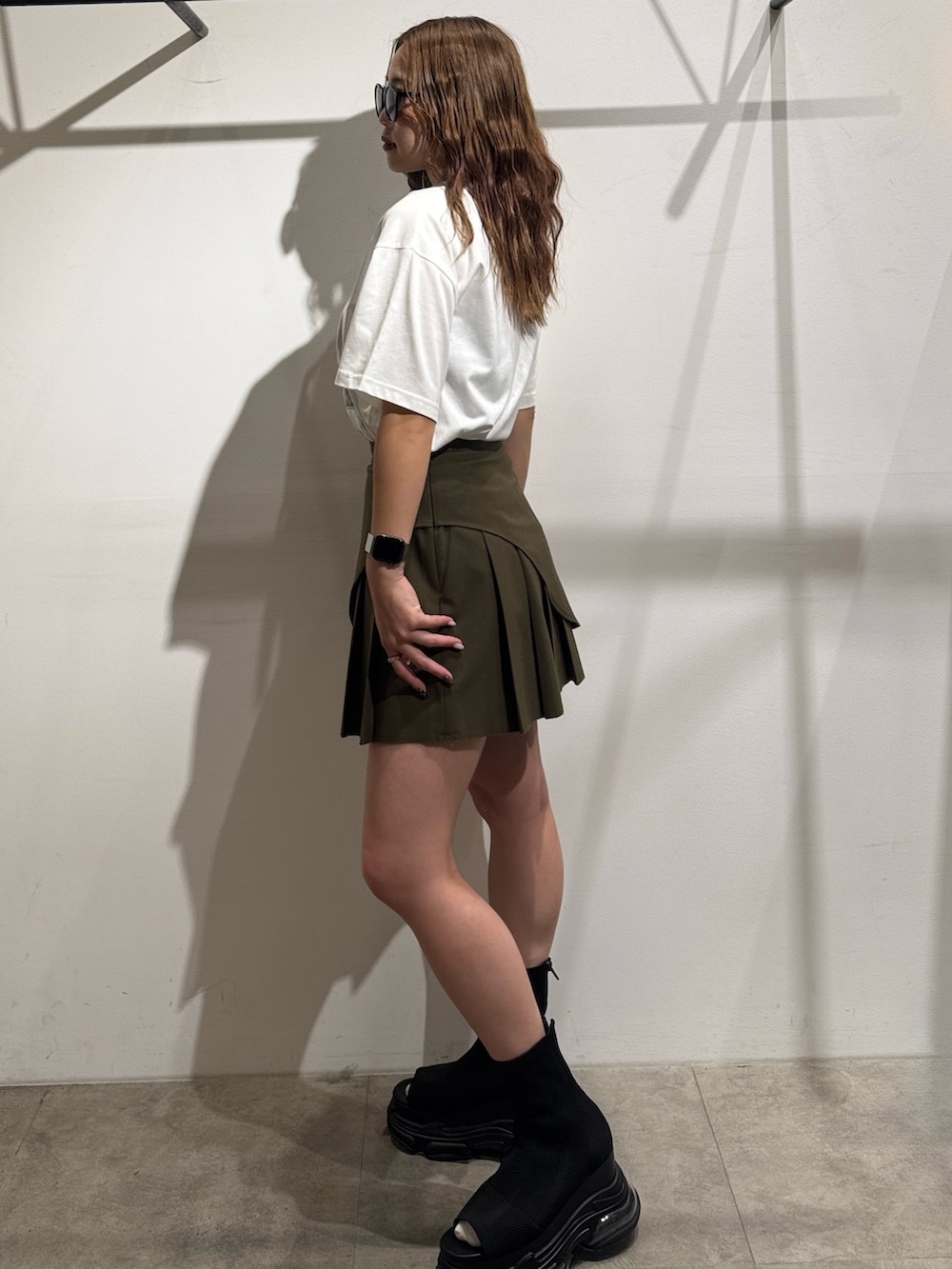 グリーン系のスカート、ホワイト系のTシャツ/カットソー、ブラック系のサンダルを着用したレディースの夏コーディネートの2枚目の写真