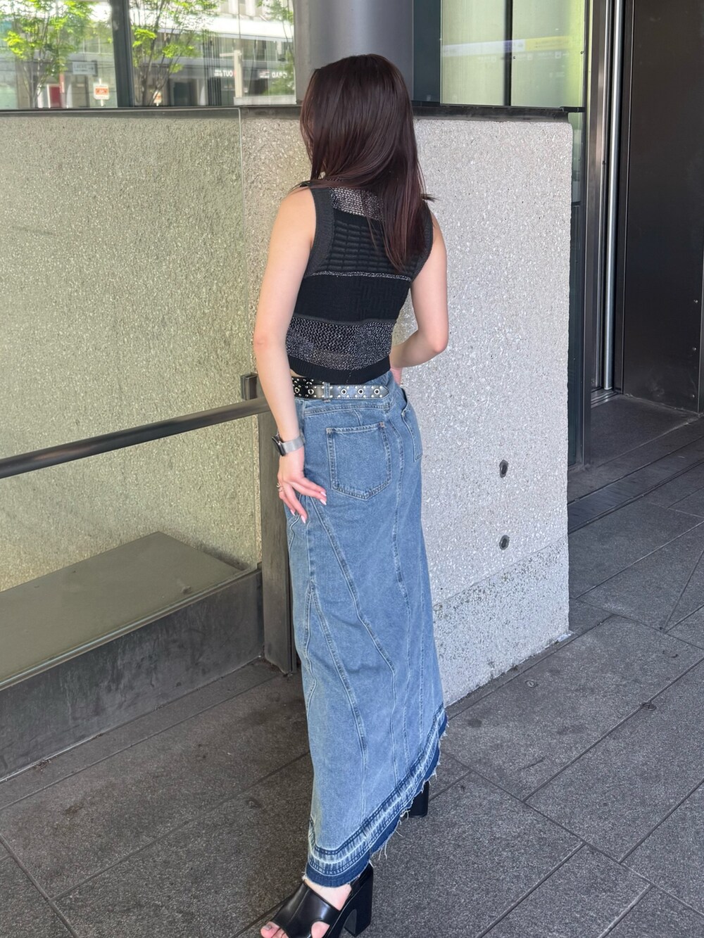 ブルー系のデニムスカート、ブラック系のタンクトップ、ブラック系のサンダルを着用したレディースの春コーディネートの2枚目の写真