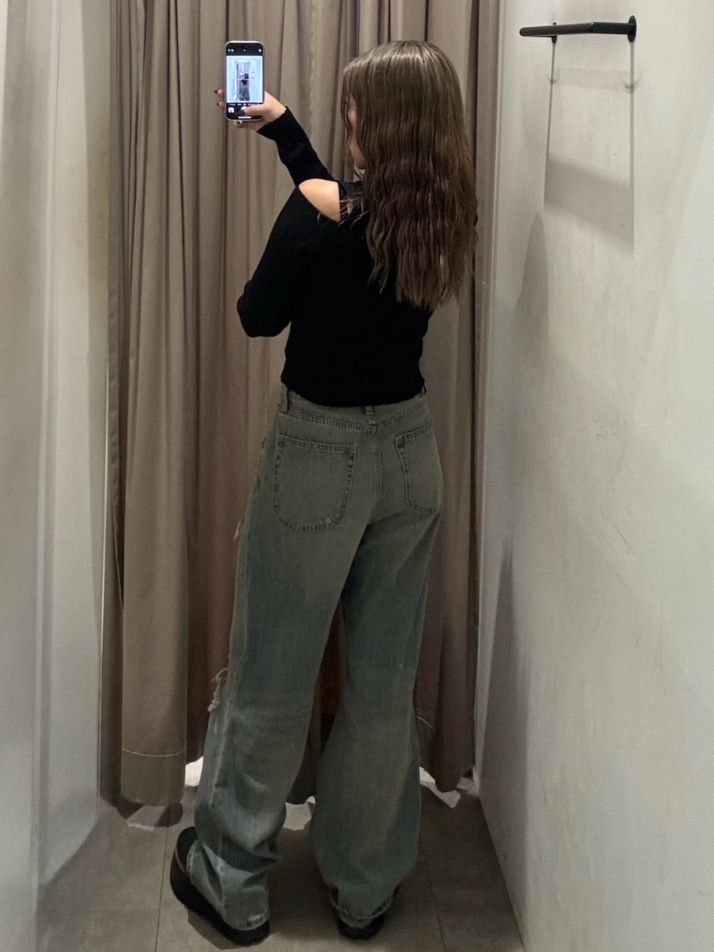 ブルー系のデニムパンツ、ブラック系のニット/セーター、ブラック系のブーツを着用したレディースの秋コーディネートの3枚目の写真