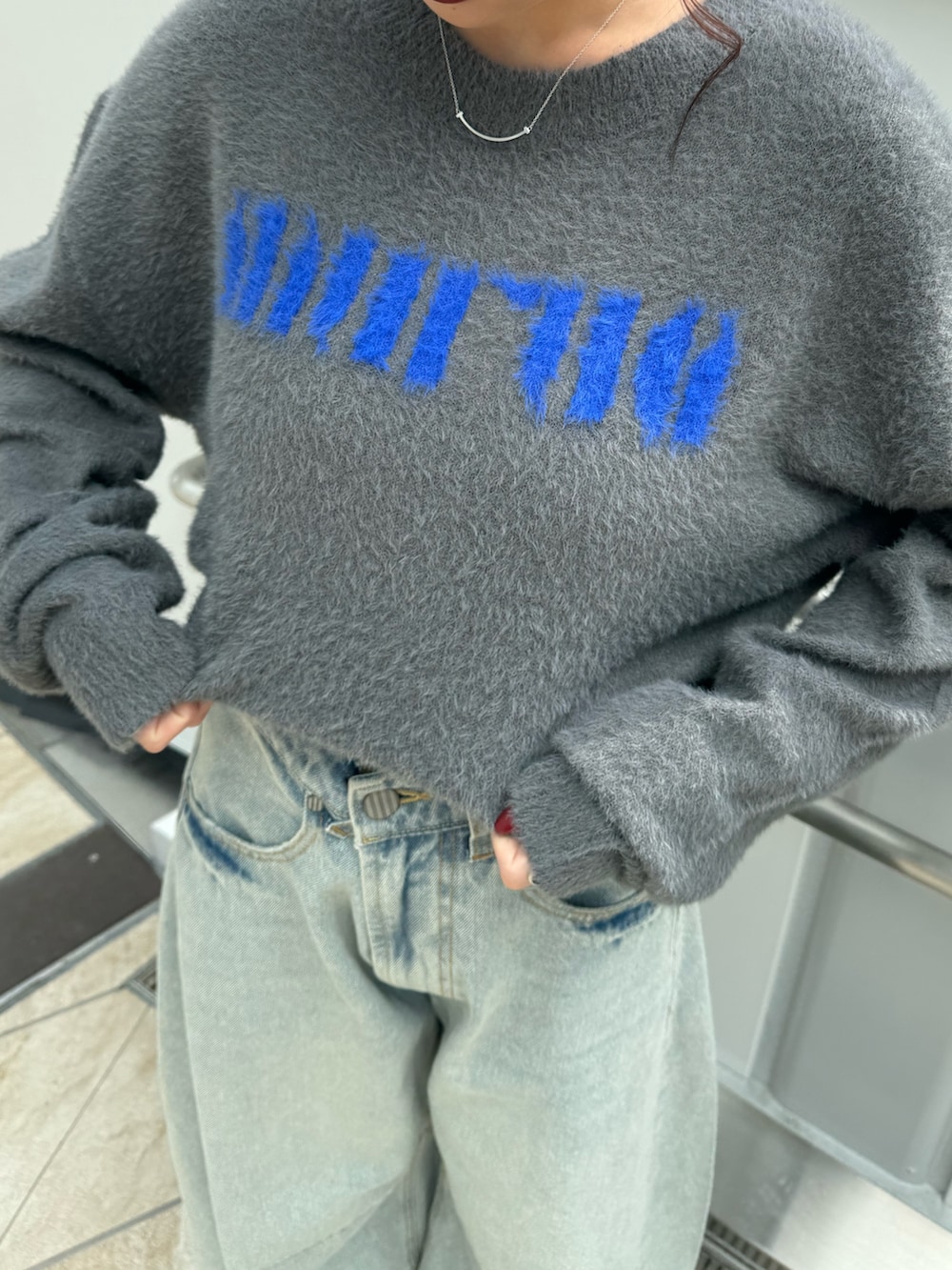 グレー系のニット/セーター、ブルー系のデニムパンツ、ブラウン系のブーツを着用したレディースの秋コーディネートの5枚目の写真