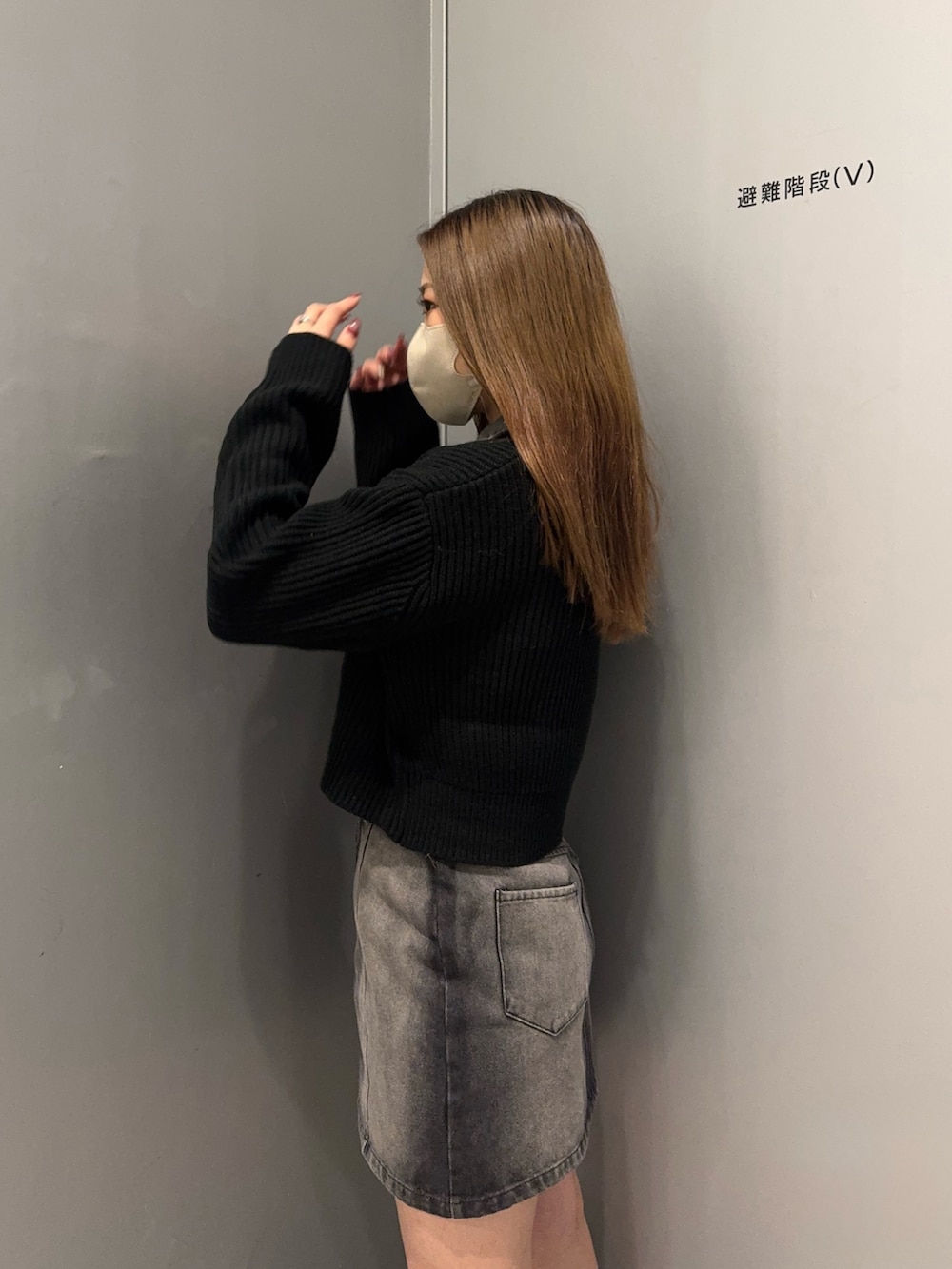 ブラック系のデニムスカート、ブラック系のニット/セーター、ブラック系のブーツを着用したレディースの冬コーディネートの5枚目の写真