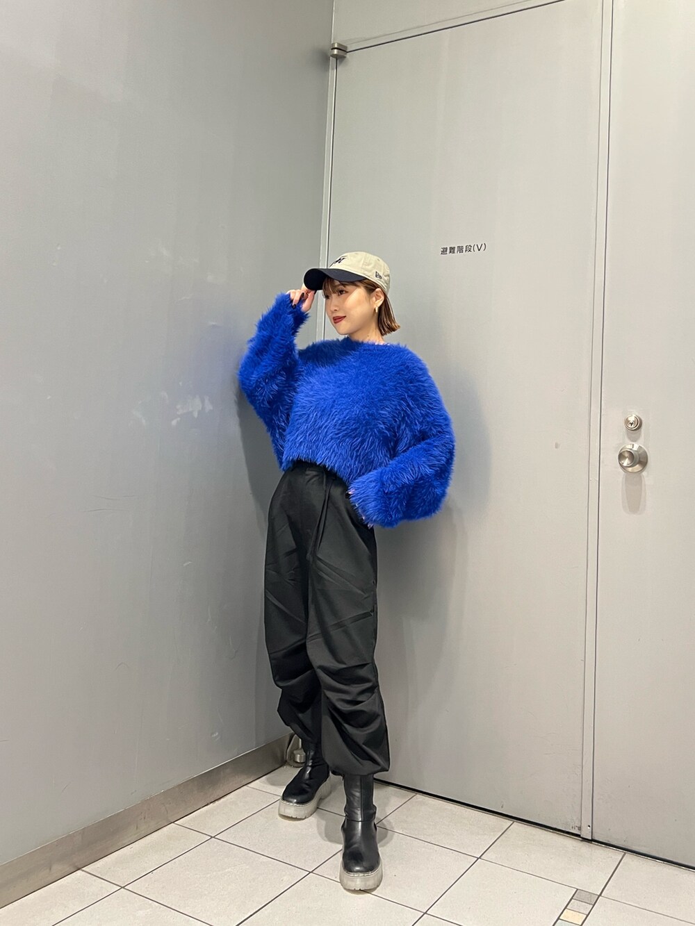 ブルー系のニット/セーター、ブラック系のその他パンツ、ブラック系のブーツを着用したレディースの秋コーディネートの3枚目の写真