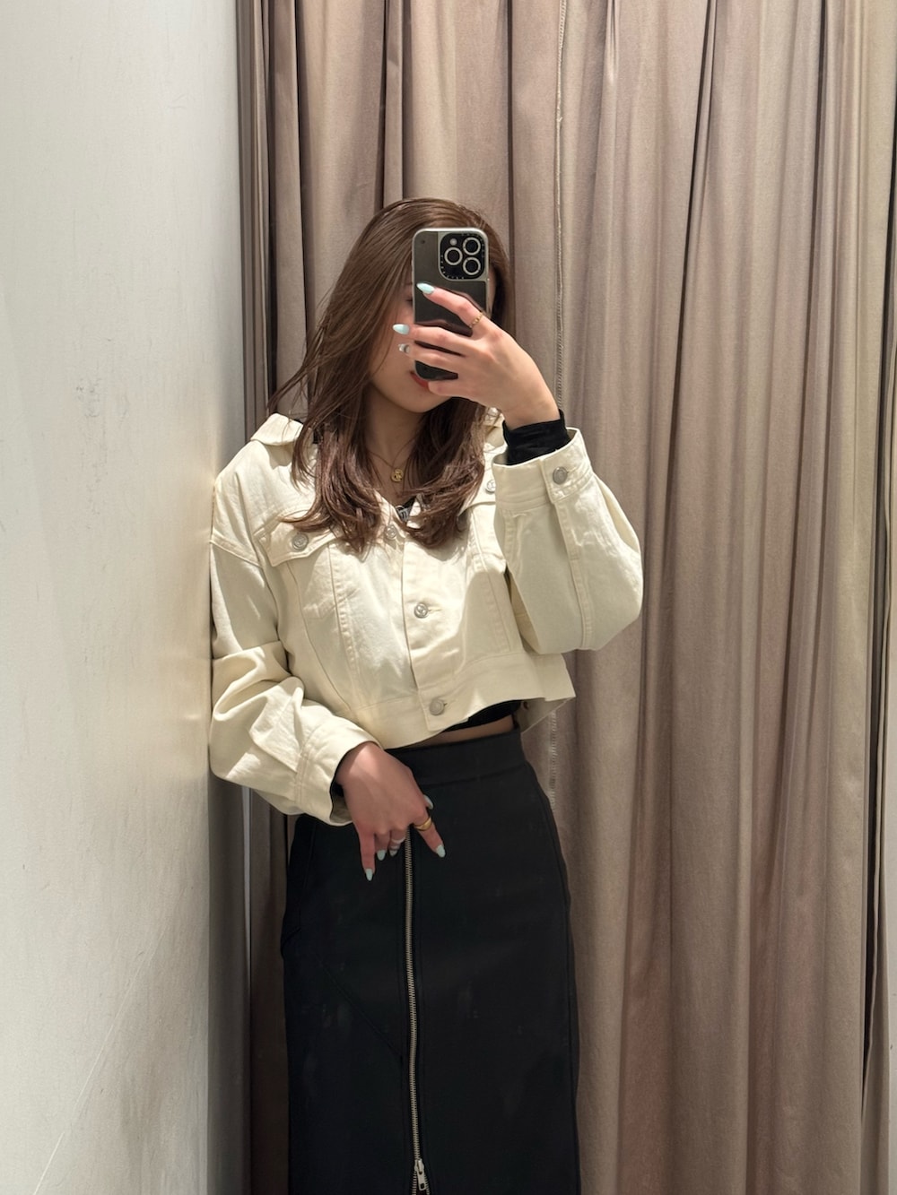 ブラック系のスカート、ホワイト系のデニムジャケット、ブラック系のブーツを着用したレディースの冬コーディネートの4枚目の写真