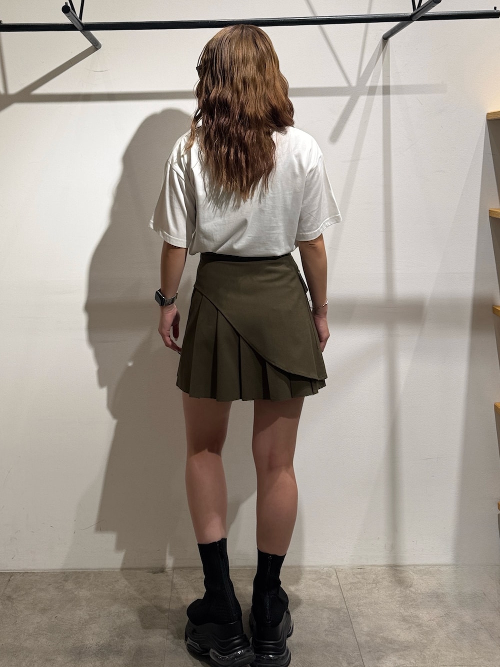 グリーン系のスカート、ホワイト系のTシャツ/カットソー、ブラック系のサンダルを着用したレディースの夏コーディネートの3枚目の写真