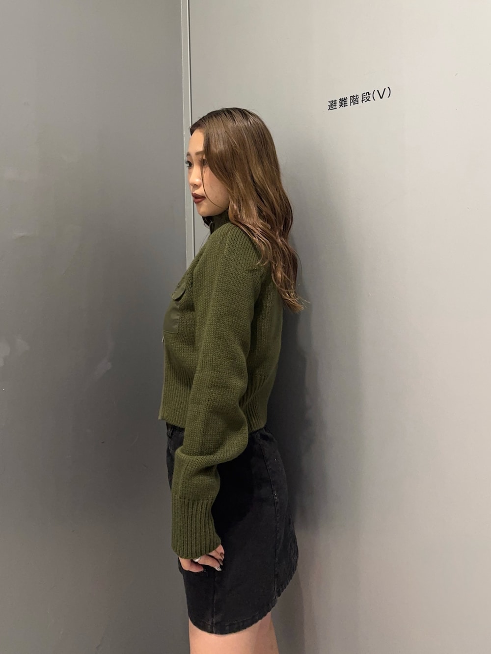 ブラック系のスカート、グリーン系のニット/セーター、ブラック系のブーツを着用したレディースの秋コーディネートの5枚目の写真