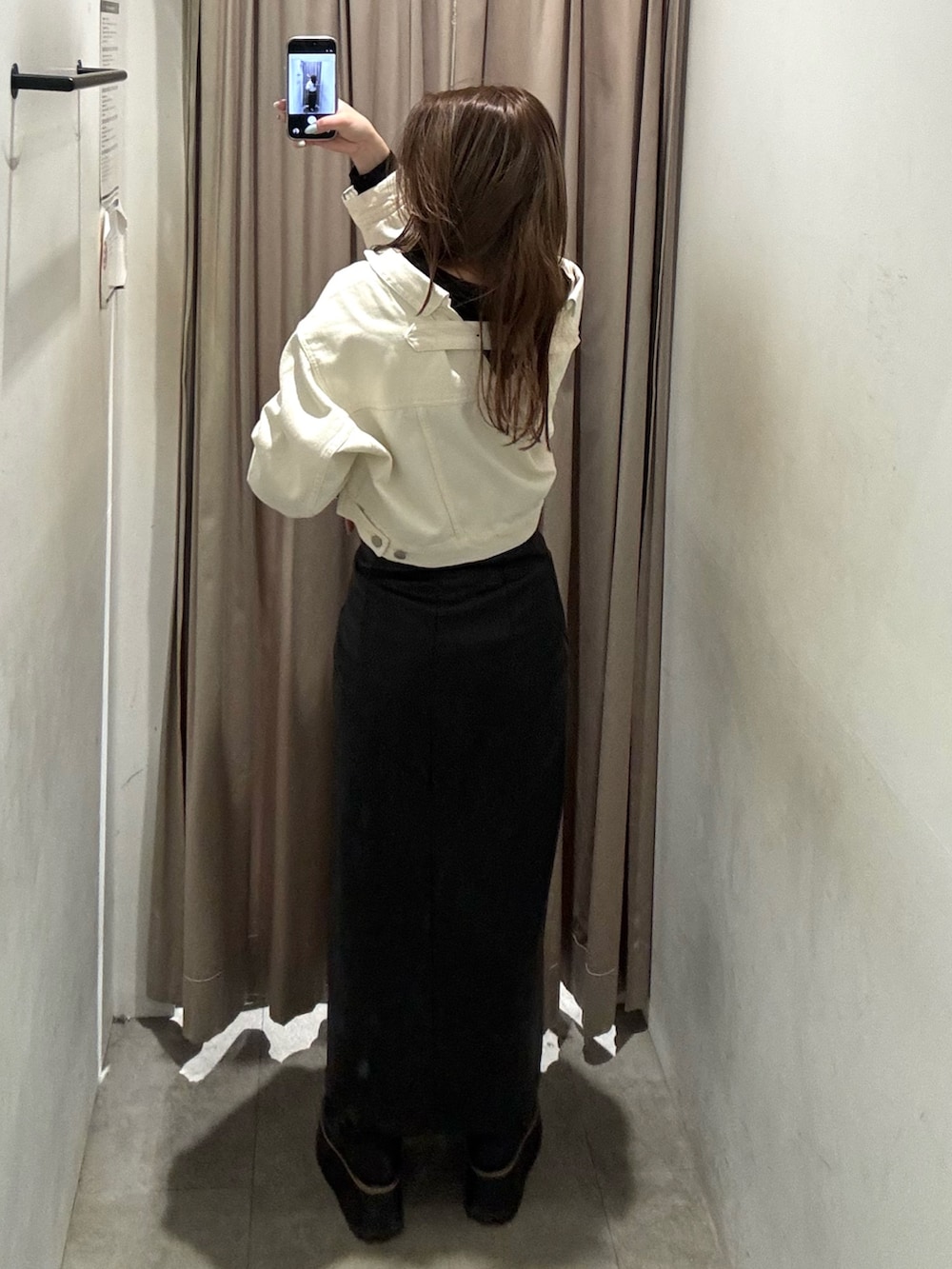 ブラック系のスカート、ホワイト系のデニムジャケット、ブラック系のブーツを着用したレディースの冬コーディネートの3枚目の写真