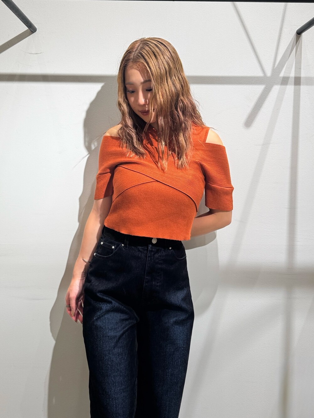 オレンジ系のニット/セーター、ブラック系のデニムパンツ、ブラック系のブーツを着用したレディースの夏コーディネートの5枚目の写真