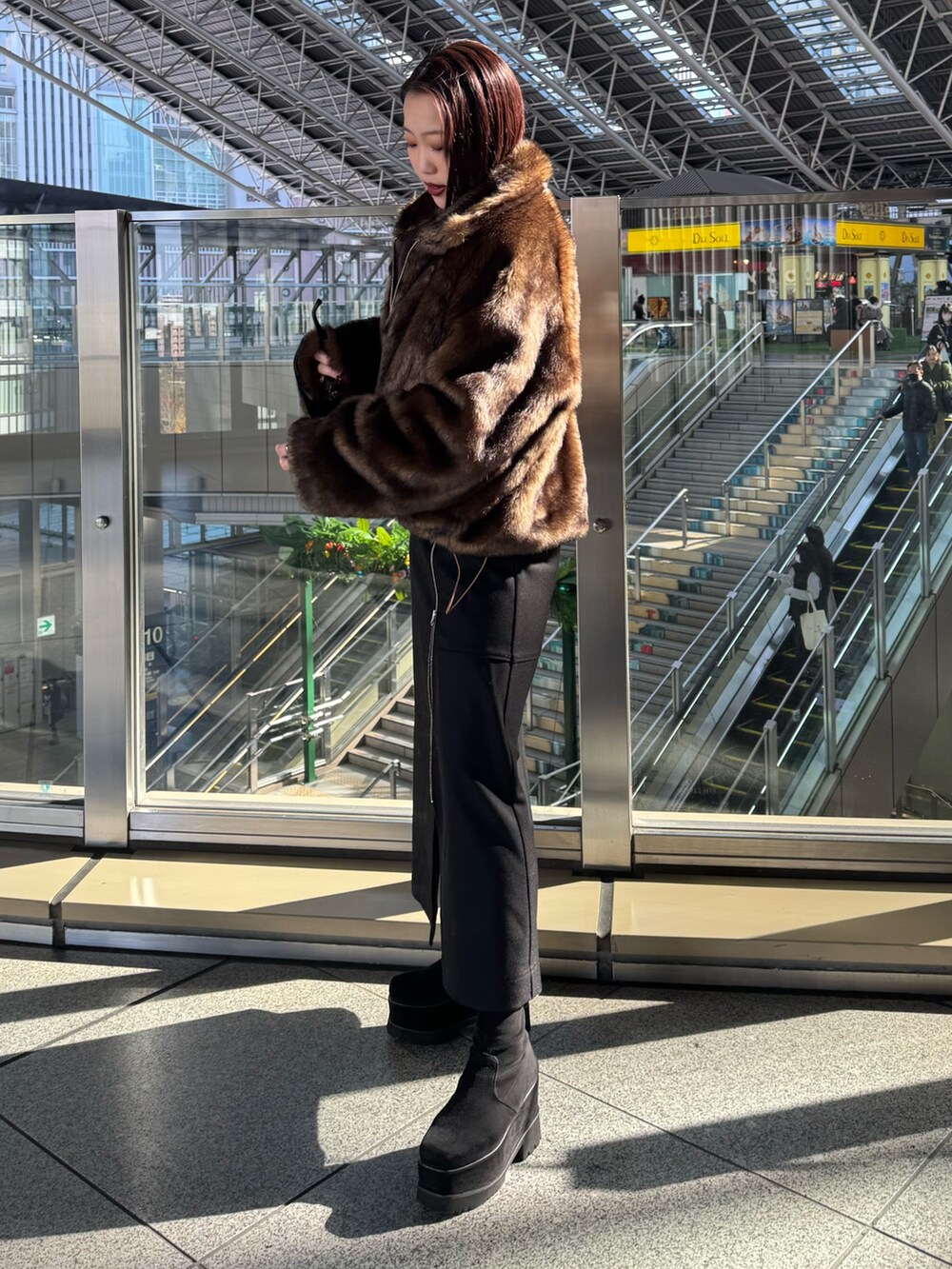 ブラウン系のブルゾン、ブラック系のスカート、ブラック系のブーツを着用したレディースの冬コーディネートの2枚目の写真