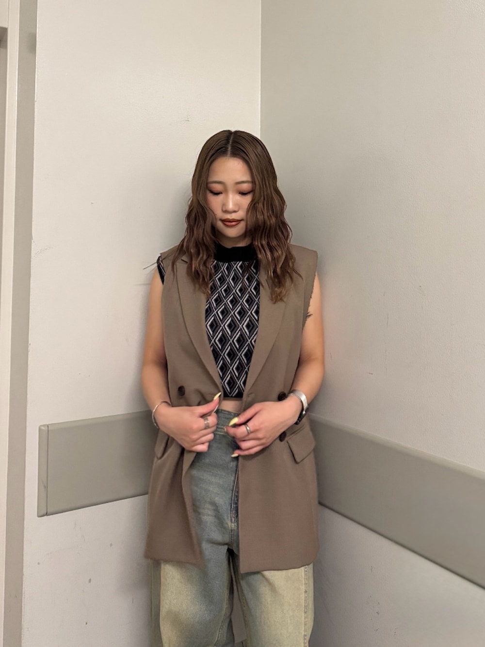 ブラック系のタンクトップ、ブラウン系のベスト、ブルー系のデニムパンツを着用したレディースの夏コーディネートの4枚目の写真