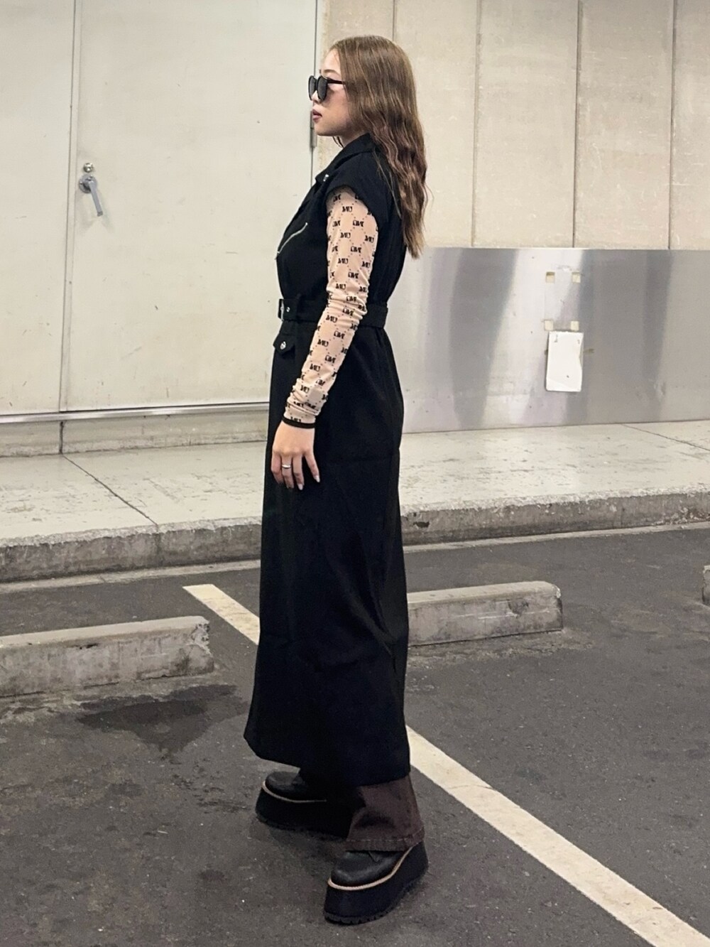 ブラウン系のデニムパンツ、ベージュ系のTシャツ/カットソー、ブラック系のワンピースを着用したレディースの秋コーディネートの2枚目の写真