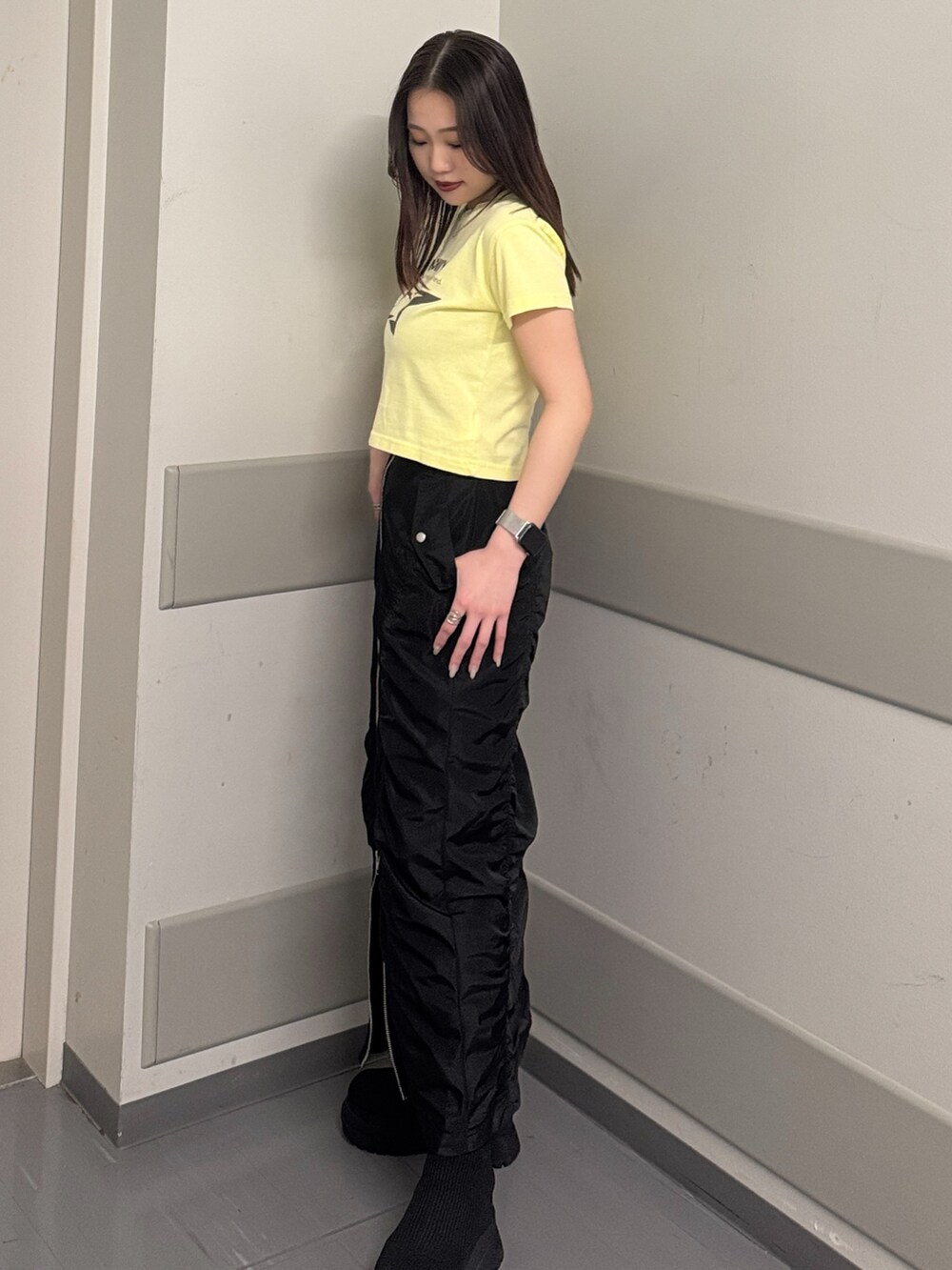 イエロー系のTシャツ/カットソー、ブラック系のスカート、ブラック系のブーツを着用したレディースの春コーディネートの2枚目の写真