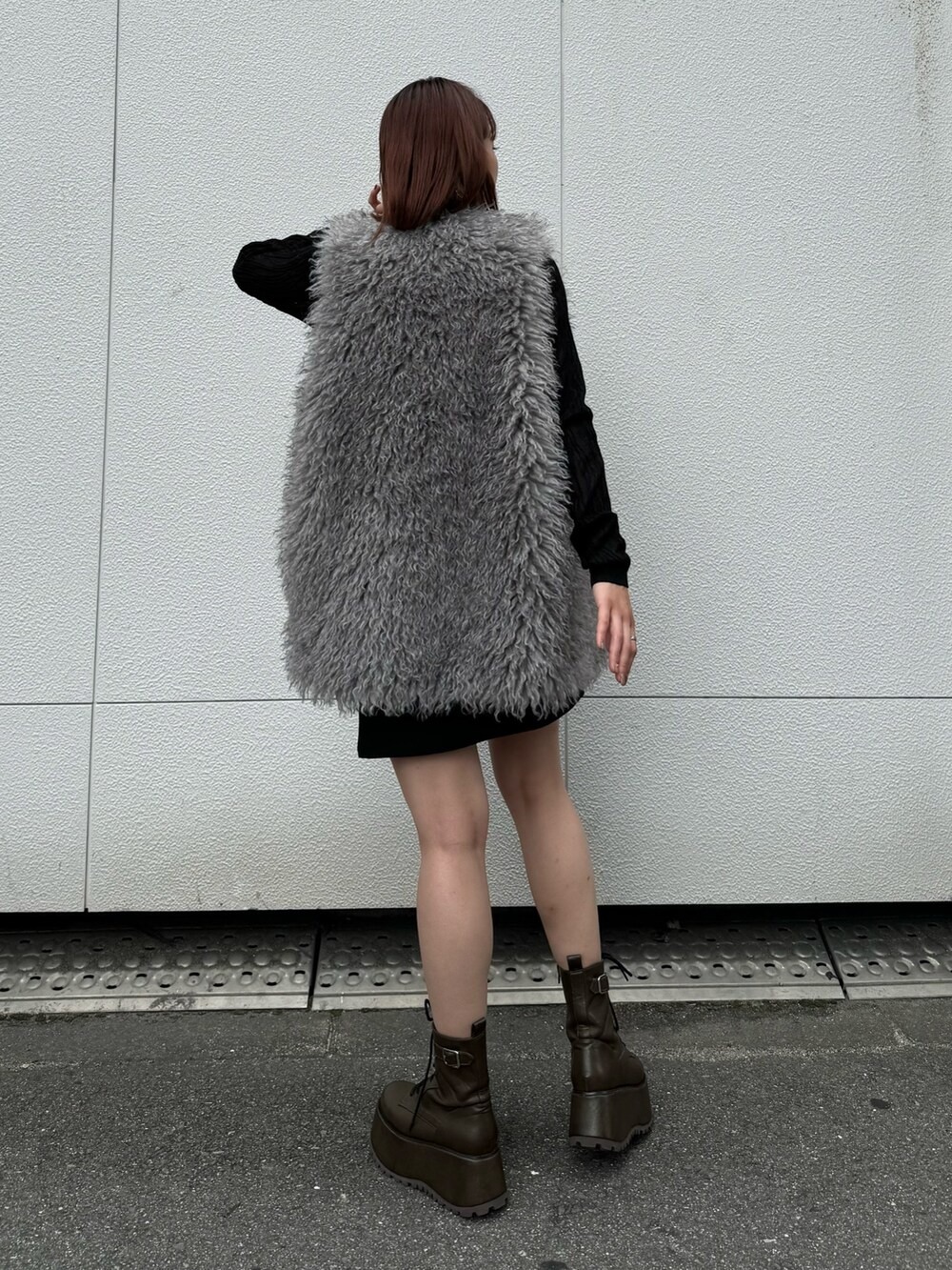 ブラック系のニット/セーター、グレー系のベスト、ブラック系のスカートを着用したレディースの秋コーディネートの3枚目の写真