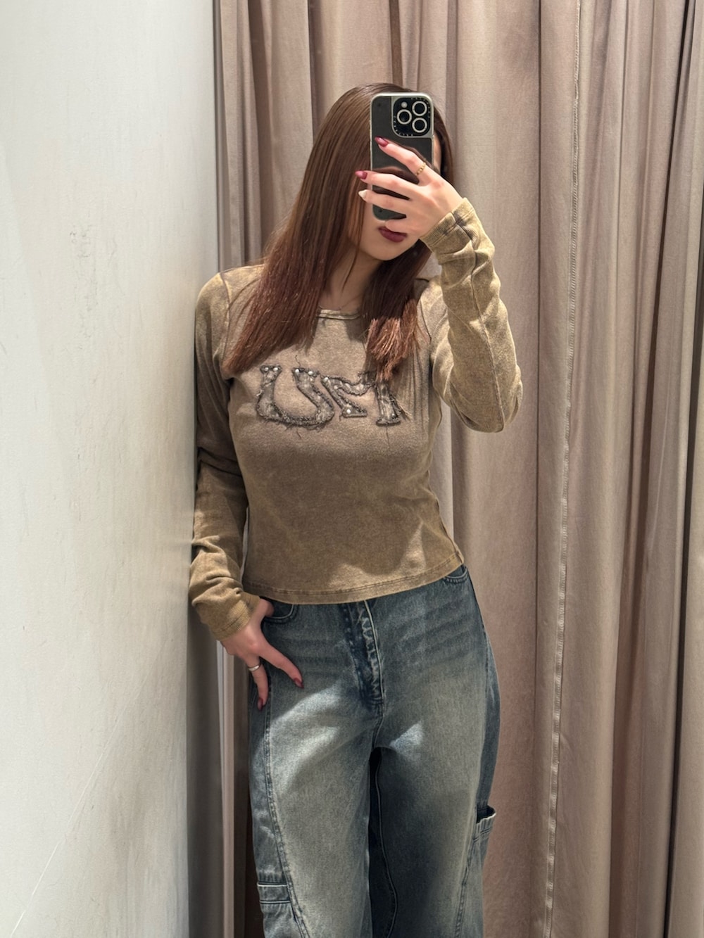 ブルー系のデニムパンツ、ブラウン系のTシャツ/カットソー、ブラック系のブーツを着用したレディースの冬コーディネートの4枚目の写真