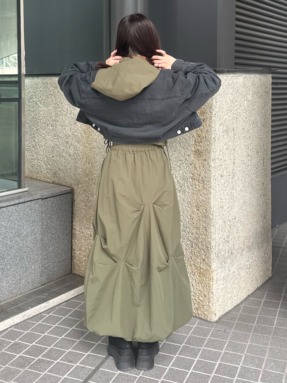 ブラック系のデニムジャケット、ベージュ系のベスト、グリーン系のスカートを着用したレディースの春コーディネートの3枚目の写真