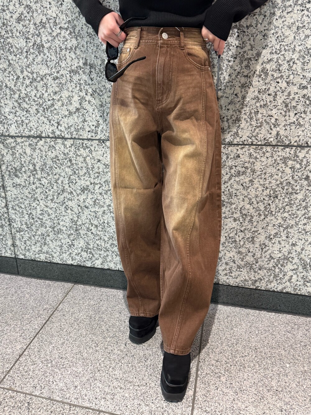 ブラック系のニット/セーター、ホワイト系のムートンコート、ブラウン系のデニムパンツを着用したレディースの冬コーディネートの6枚目の写真