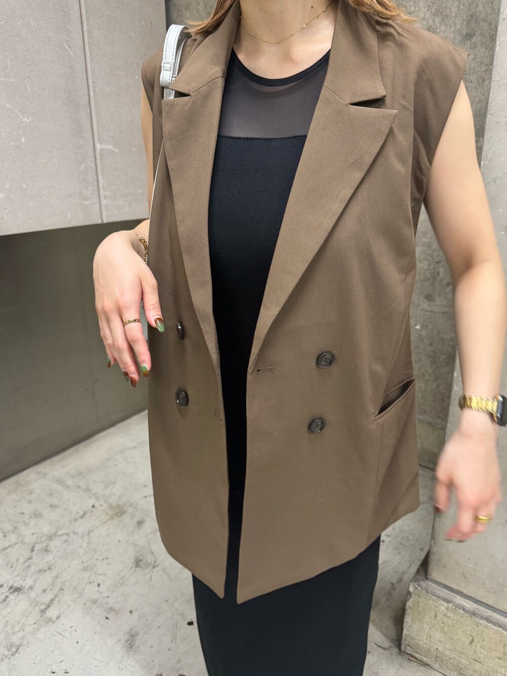 ブラウン系のベスト、ブラック系のワンピース、シルバー系のハンドバッグを着用したレディースの夏コーディネートの6枚目の写真