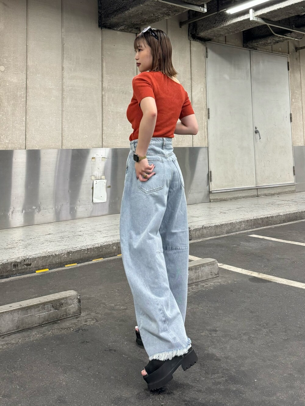 オレンジ系のニット/セーター、ブルー系のデニムパンツを着用したレディースの夏コーディネートの3枚目の写真