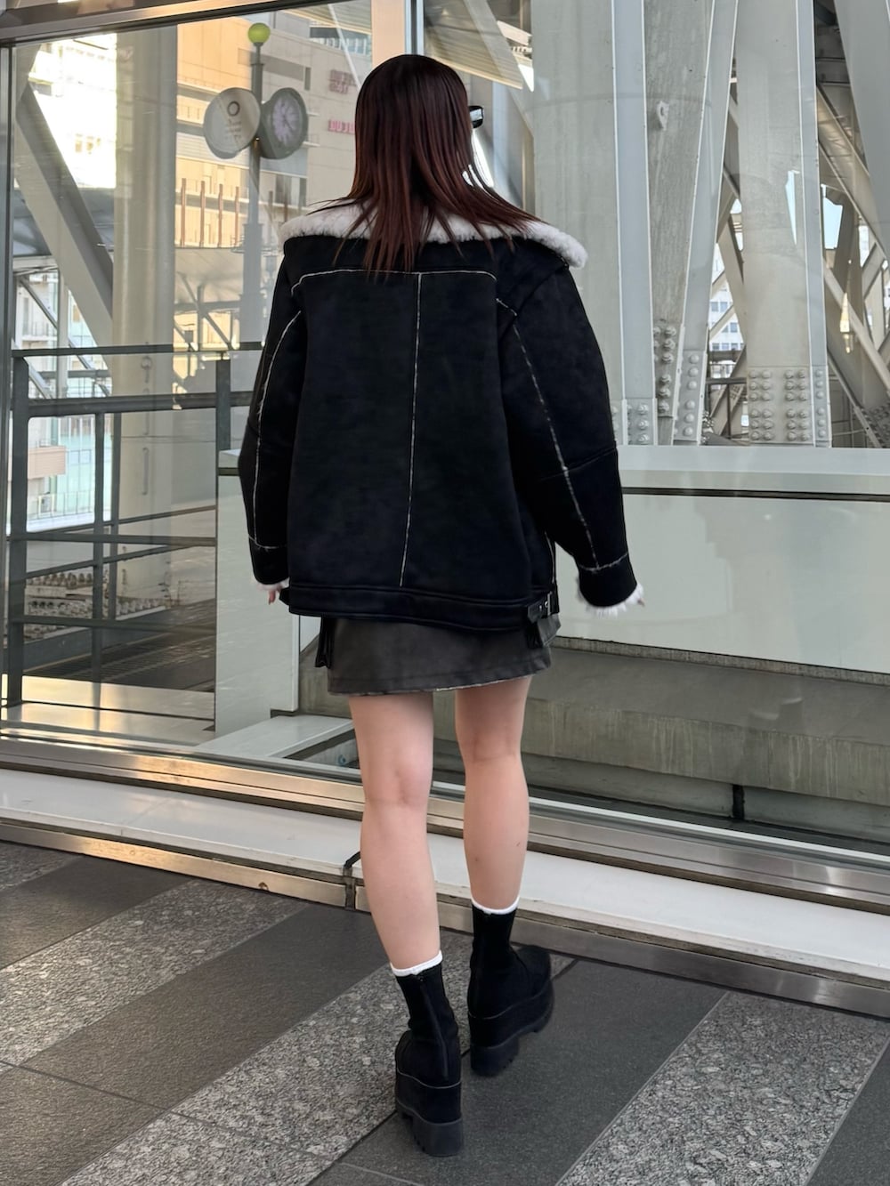 レッド系のニット/セーター、ブラウン系のスカート、ブラック系のムートンコートを着用したレディースの冬コーディネートの3枚目の写真