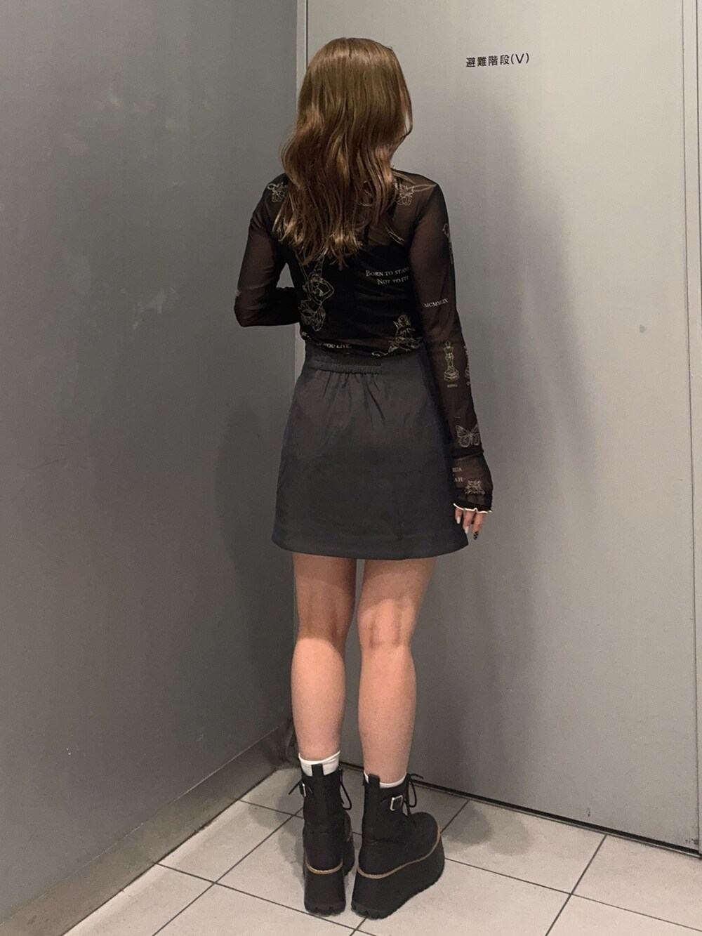 ブラック系のTシャツ/カットソー、グレー系のスカート、ブラック系のブーツを着用したレディースの秋コーディネートの3枚目の写真