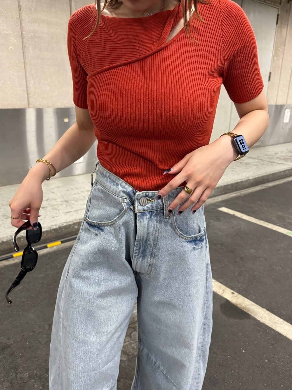 オレンジ系のニット/セーター、ブルー系のデニムパンツを着用したレディースの夏コーディネートの6枚目の写真