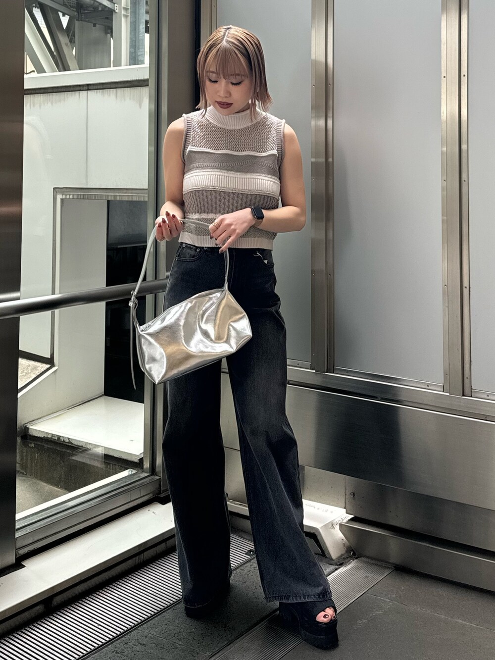 グレー系のニット/セーター、ブラック系のデニムパンツを着用したレディースの春コーディネートの2枚目の写真