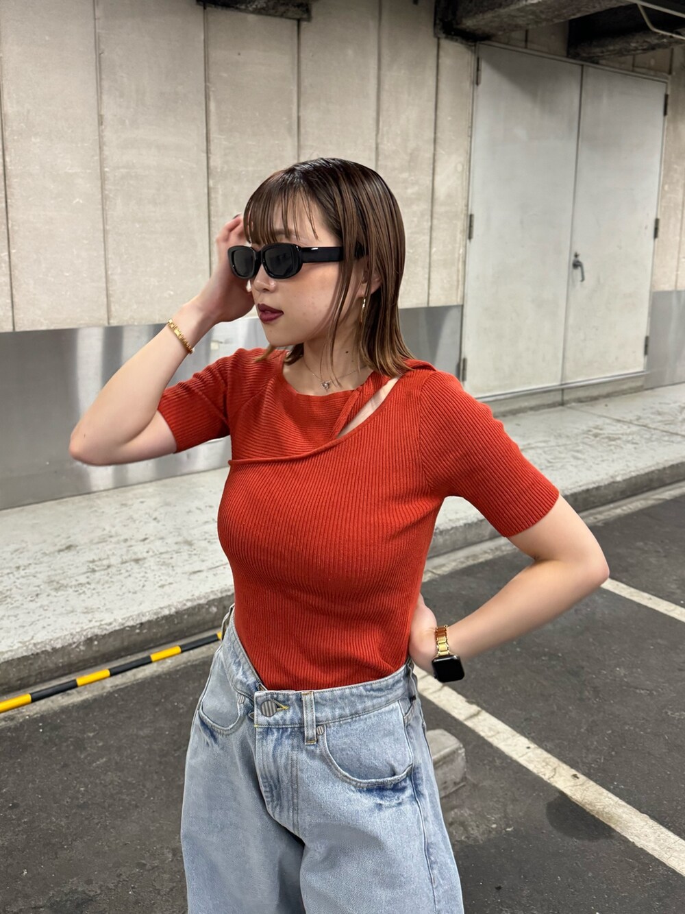 オレンジ系のニット/セーター、ブルー系のデニムパンツを着用したレディースの夏コーディネートの5枚目の写真