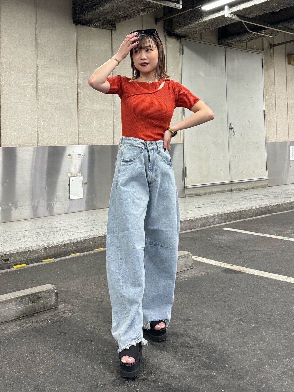 オレンジ系のニット/セーター、ブルー系のデニムパンツを着用したレディースの夏コーディネートの4枚目の写真