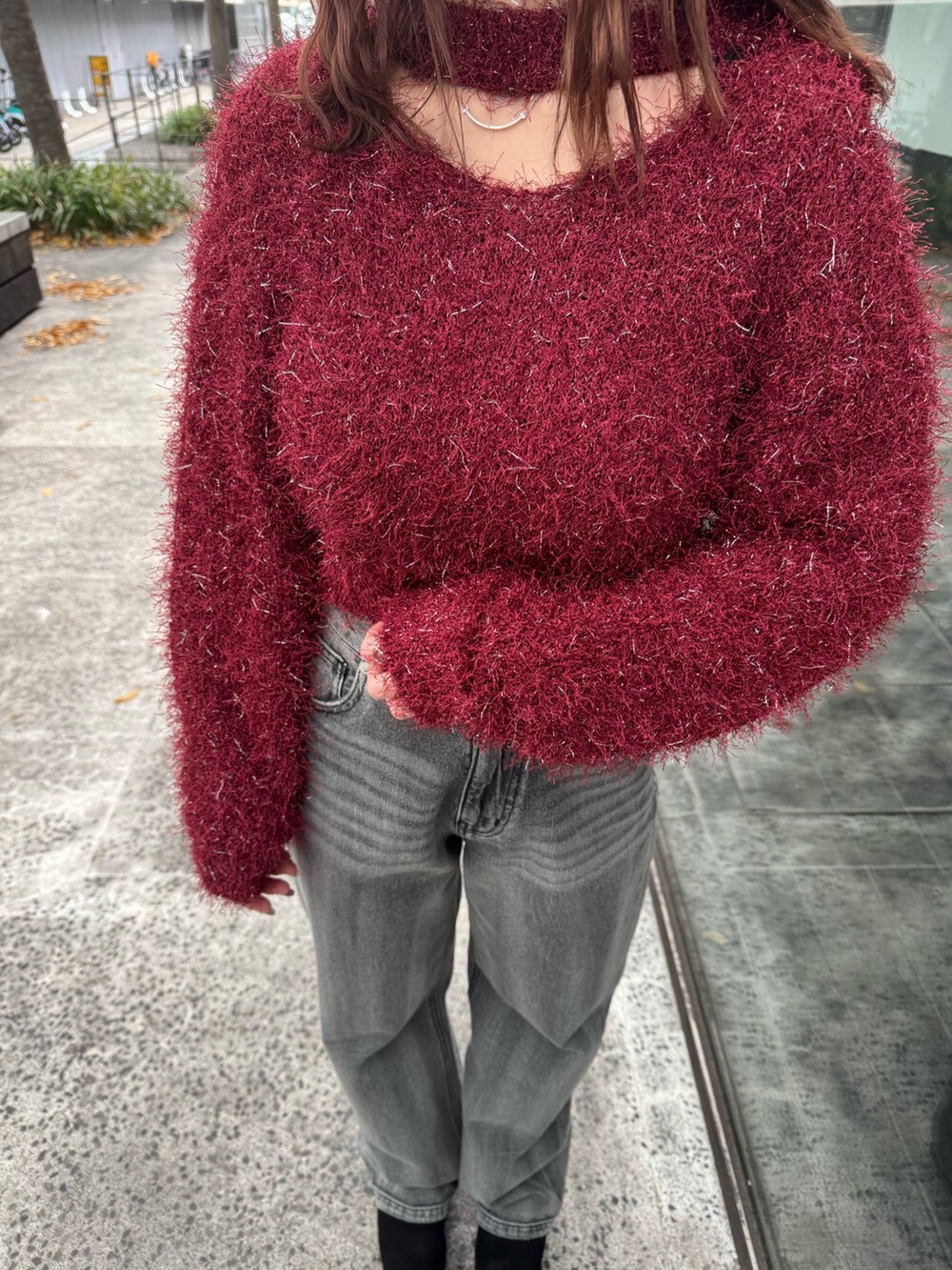 レッド系のニット/セーター、ブラック系のデニムパンツ、ブラック系のブーツを着用したレディースの冬コーディネートの5枚目の写真