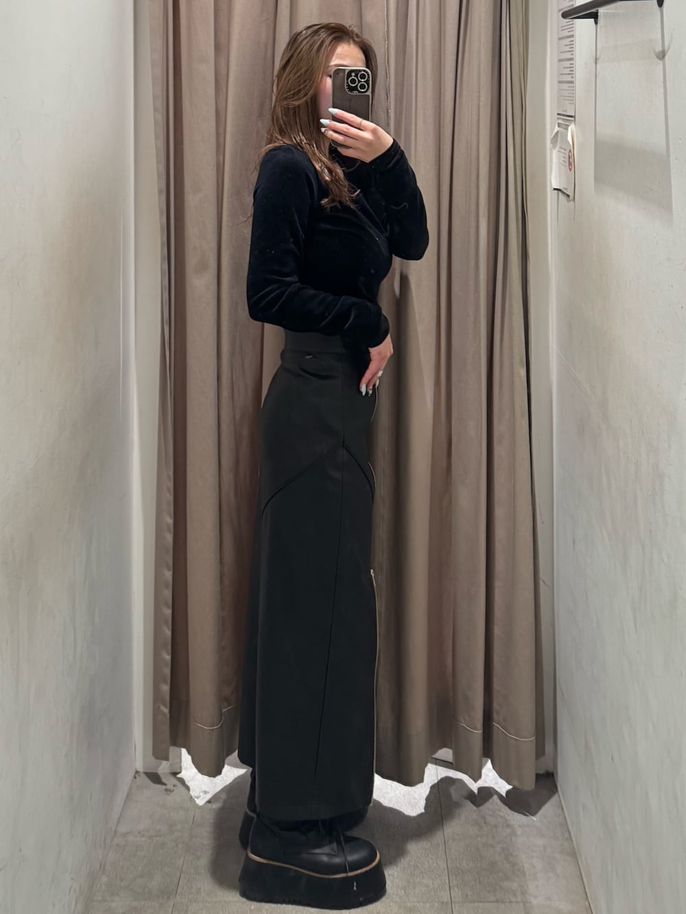 ブラック系のスカート、ブラック系のTシャツ/カットソー、ブラック系のブーツを着用したレディースの冬コーディネートの2枚目の写真