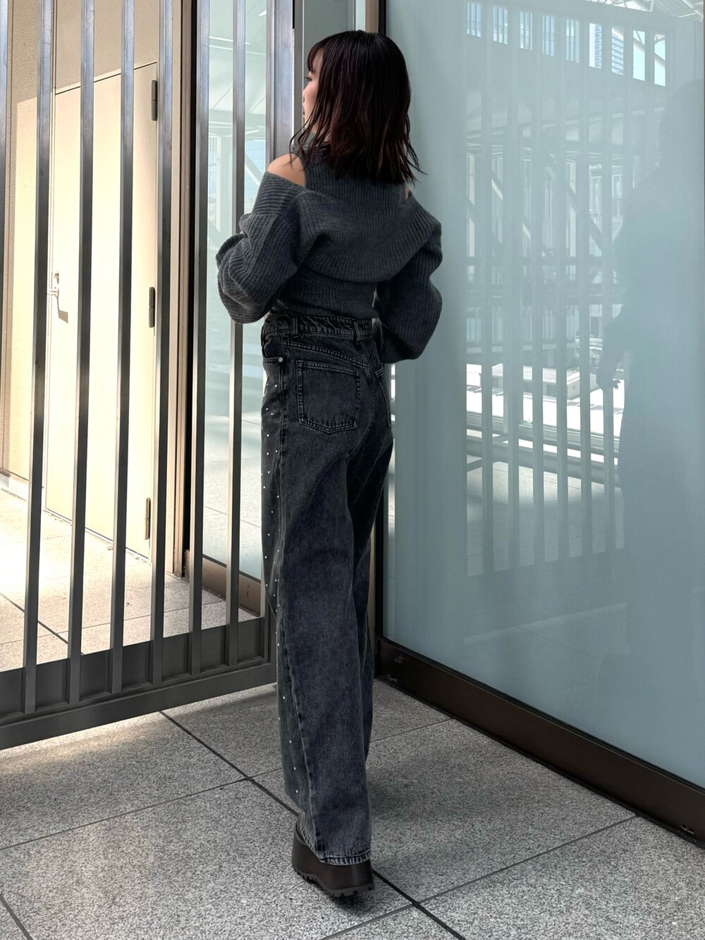 グレー系のニット/セーター、ブラック系のデニムパンツ、ブラウン系のブーツを着用したレディースの秋コーディネートの4枚目の写真