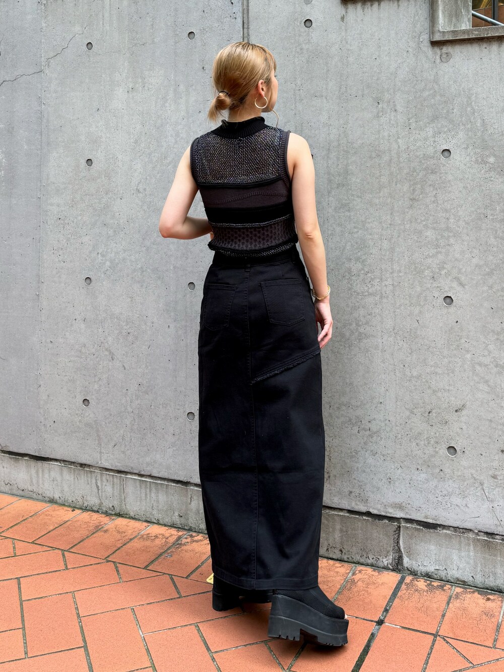 ブラック系のニット/セーター、ブラック系のデニムスカートを着用したレディースの夏コーディネートの4枚目の写真