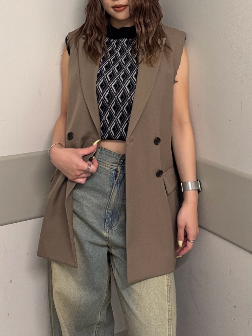 ブラック系のタンクトップ、ブラウン系のベスト、ブルー系のデニムパンツを着用したレディースの夏コーディネートの5枚目の写真