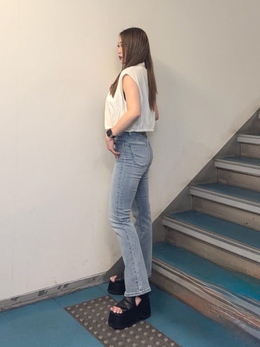ブラック系のブーツ、ブルー系のデニムパンツ、ホワイト系のシャツ/ブラウスを着用したレディースの夏コーディネートの2枚目の写真