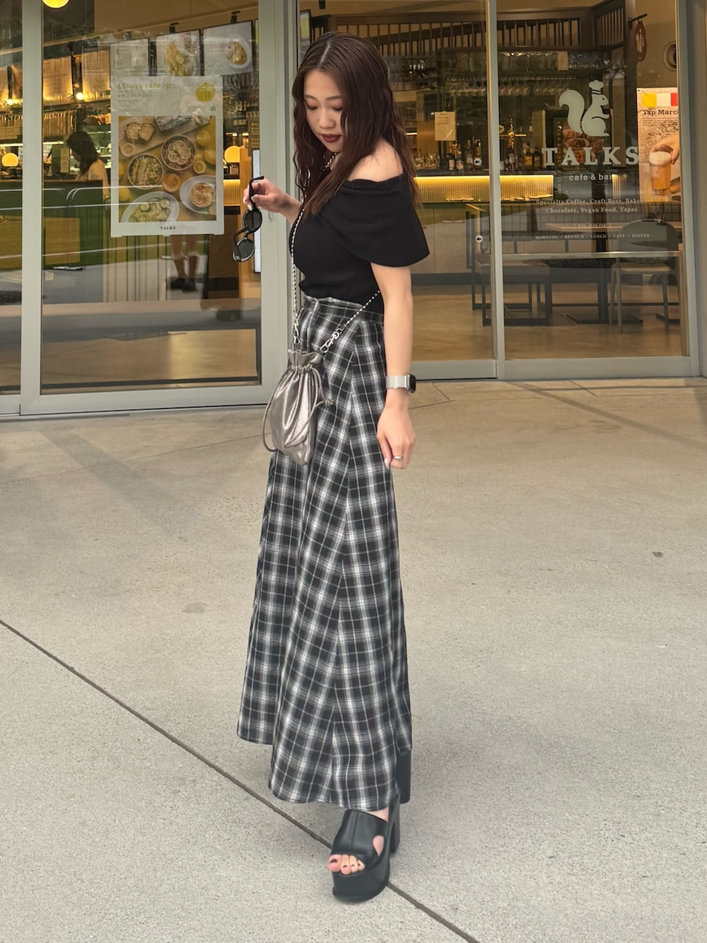 ブラック系のスカート、ブラック系のニット/セーター、ブラック系のサンダルを着用したレディースの夏コーディネートの2枚目の写真