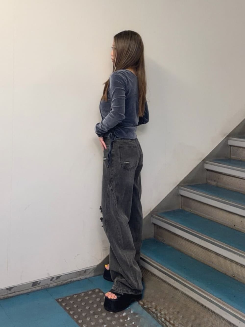 グレー系のデニムパンツ、ブラック系のブーツ、ブルー系のTシャツ/カットソーを着用したレディースの秋コーディネートの2枚目の写真