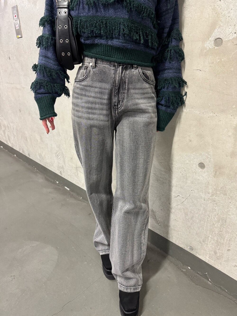 グリーン系のニット/セーター、ブラック系のデニムパンツ、ブラック系のブーツを着用したレディースの冬コーディネートの6枚目の写真